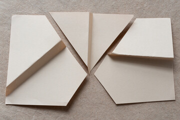 beige stationery sheet cut and folded and arranged on plain brown paper