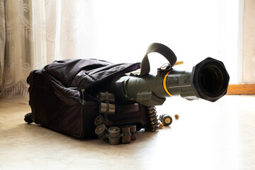 An anti-tank grenade launcher and machine gun belts stick out from a suitcase on the floor in an apartment in Ukraine, weapons in a suitcase, travel, transportation of weapons