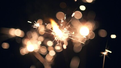 Celebrating holidays. New Year. Christmas. Lightening shining sparkler on black background. Close-up Bengal lights are burning on a dark background. Slow Motion HD shot - Powered by Adobe