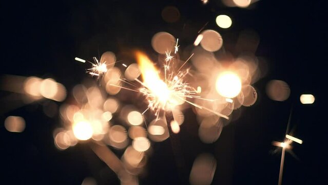 Celebrating holidays. New Year. Christmas. Lightening shining sparkler on black background. Close-up Bengal lights are burning on a dark background. Slow Motion HD shot