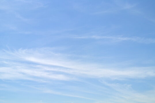 Clear blue sky with white cirrus clouds, small and large wispy, feathery, fluffy clouds alternating and moving slowly, nature background
