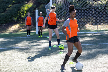 Group of five female soccer players on a team warming up and running calisthenics during practice exercise for the sport.