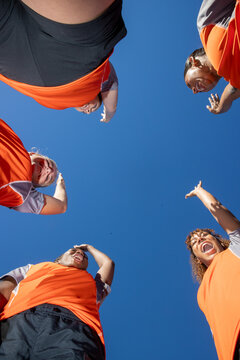 Looking up at a team of female soccer players. The women are joined in unity and cheering before a match. 