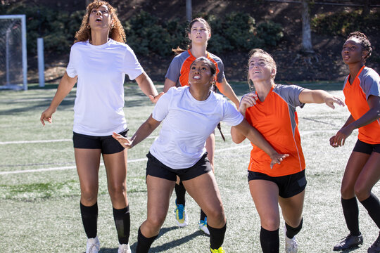 Female soccer players play in an intense and competitive game on the field outside. 