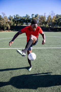 African American man playing with a soccer ball on the field. 