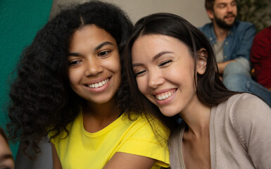 Close up photo of smiling multi ethnic girl friends sitting on the stairs in the school or college...
