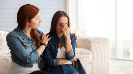 Close up photo of two women friends on couch at home, one girl calming down her friend. Break in...