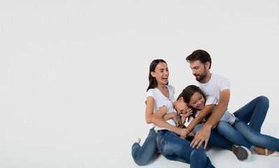 Happy excited beautiful and smiling dad, mommy and them kids sitting on the floor isolated on white background