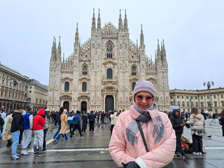 Fototapeta premium Mature and happy female tourist standing in front of the famous Duomo cathedral in Milan