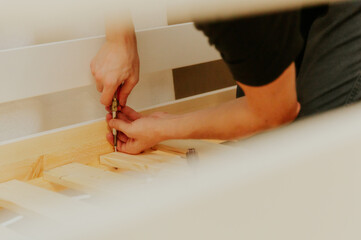 A young man installs a bunch of frame boards on a bunk bed.