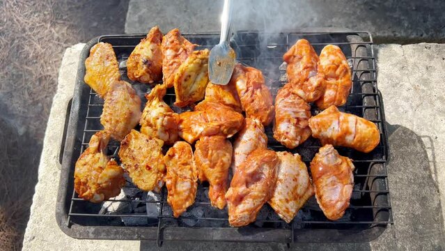 Grilled raw chicken pieces. Spicy marinated chicken wings and legs on barbecue, BBQ grill. Close up
