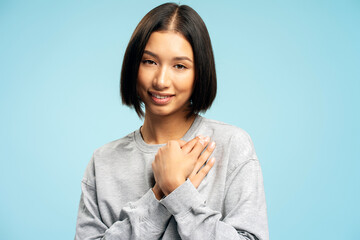 Smiling Asian woman with stylish bob hairstyle holding hands, gesturing, thanking, looking at camera