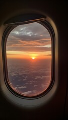 Airplane window view on a clouds and sunset outside of aircraft