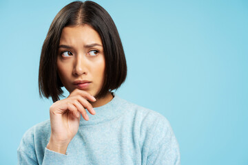 Pensive woman with stylish hairstyle wearing casual sweater choosing something and looking away