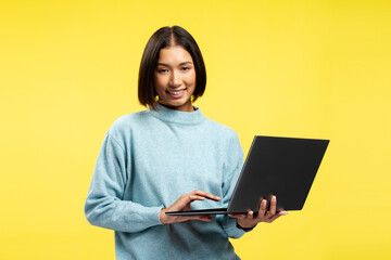 Beautiful smiling Asian woman using laptop wearing stylish casual sweater typing on keyboard