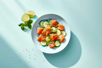 Fotobehang Salted salmon salad with fresh green lettuce,cucumbers.Lunch bowl on a ketogenic,keto or paleo diet.Top view with lemon elements next to it on a light blue background with space for text.generative ai © Ivan