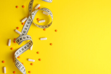 centimeter tape and pills on a colored background with space for text. concept of losing weight,...