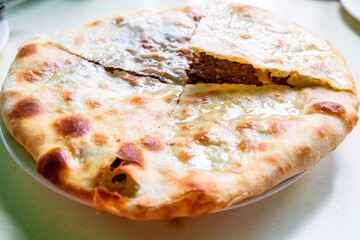 travel to Georgia - open kubdari (Georgian filled with meat bread) on plate on table close-up in local cafe in Batumi city