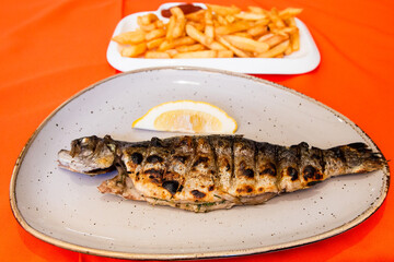 travel to Georgia - fried Georgian river trout on plate and French fries on side in local cafe in Batumi city