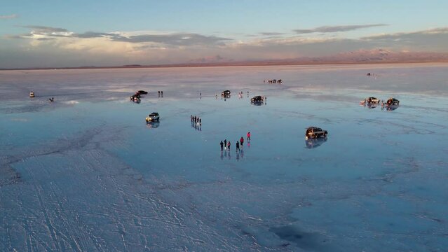 Camera rising up showing Tourist taking picure of their reflections in the water of the Salt flats on Salar De Uyuni in Bolivia