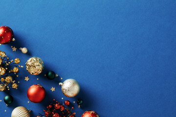 Blue Christmas background with berry branches and Christmas baubles. Xmas greeting card design.