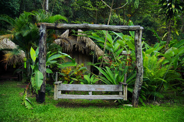 Wooden swing surrounded by lush plants.
