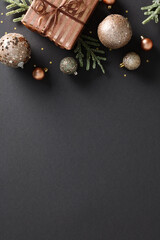 Christmas vertical banner design with bronze gift box and balls on black background. Flat lay, top view