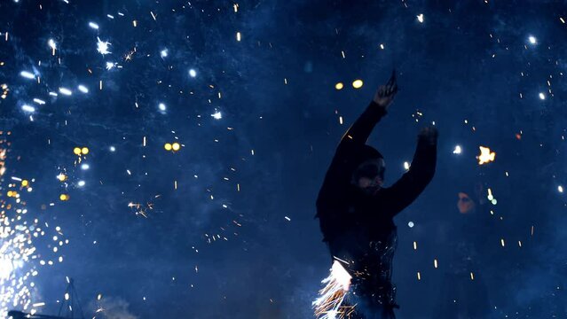 Female performer dancer with fireworks. Woman in black suit rotates the stage props producing sparks of firework.