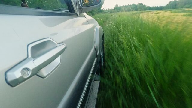 Side view of a car driving through grass on dirt road in Ub, Serbia