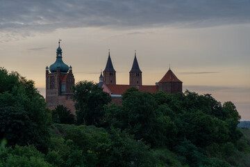 Old castle on a hill surrounded by green trees at dawn in Płock, Poland
