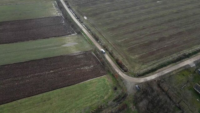 Car drives on dirt road in flooded countryside with few old houses in Ub, Serbia