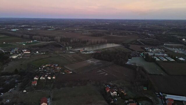 An aerial view captures the countryside lake near a village during sunset