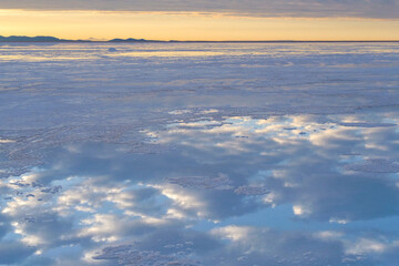 Reflections of white clouds and the blue sky on the surface of the Uyuni Salt Flat Lake, Bolivia, a popular travel destination