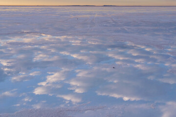 Reflections of white clouds and the blue sky on the surface of the Uyuni Salt Flat Lake, Bolivia