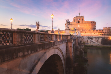View across St. Angelo Bridge over the River Tiber looking towards Castel Sant'Angelo at sunset in...