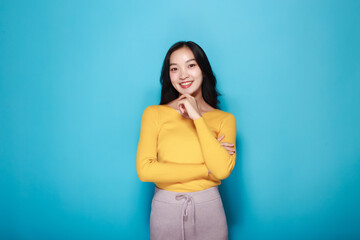 Portrait of a beautiful young woman in a light blue background, happy and smile, posting in stand position, Pretty girl makes a thoughtful expression.