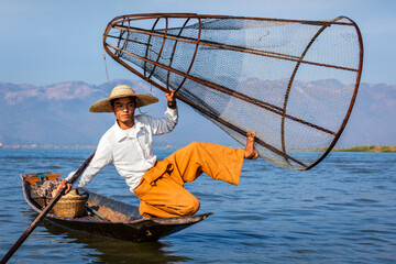 Myanmar travel attraction landmark - Traditional Burmese fisherman with fishing net at Inle lake in Myanmar famous for their distinctive one legged rowing style - obrazy, fototapety, plakaty