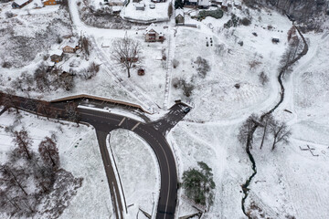 Aerial view of a road and a parking next to a natural recreation area with a small curvy creek next to a village; Lithuania