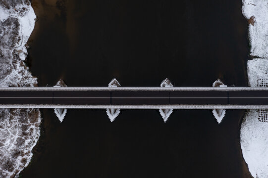 Aerial vetical view of a river bridge. High contrast pillars and banks with black water