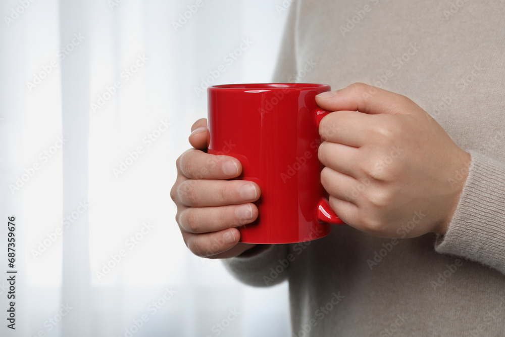 Canvas Prints Woman holding red mug indoors, closeup view