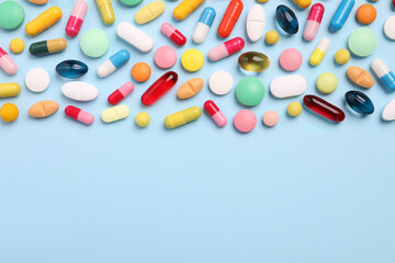 Many different pills on light blue background, flat lay. Space for text