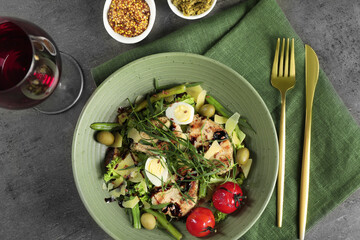 Delicious dish with tarragon, salad dressings and glass of wine served on grey table, flat lay