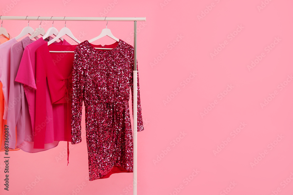 Wall mural Rack with different stylish women`s clothes on pink background, space for text