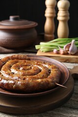 Plate with tasty homemade sausages on wooden table, closeup