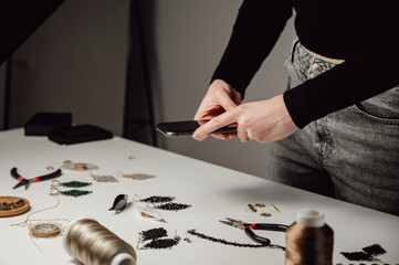 side view on Creative jewellery artist is taking photo of handmade earrings with smartphone.