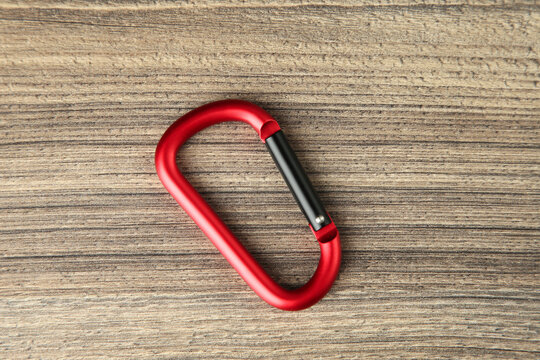 One metal carabiner on wooden table, top view