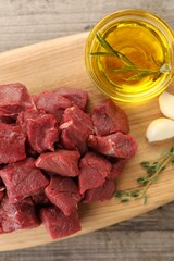 Pieces of raw beef meat, oil and garlic on wooden table, top view