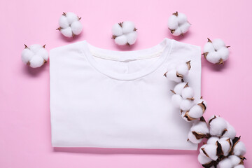 Cotton branch with fluffy flowers and white t-shirt on pink background, flat lay