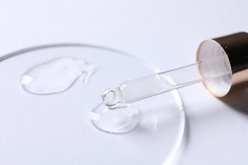 Samples of cosmetic serum and pipette on white background, closeup