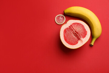 Banana, half of grapefruit and condom on red background, flat lay with space for text. Safe sex...